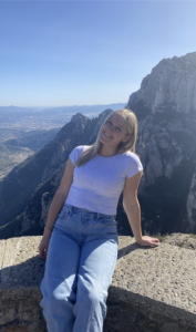 A woman smiles with a mountain behind her. 